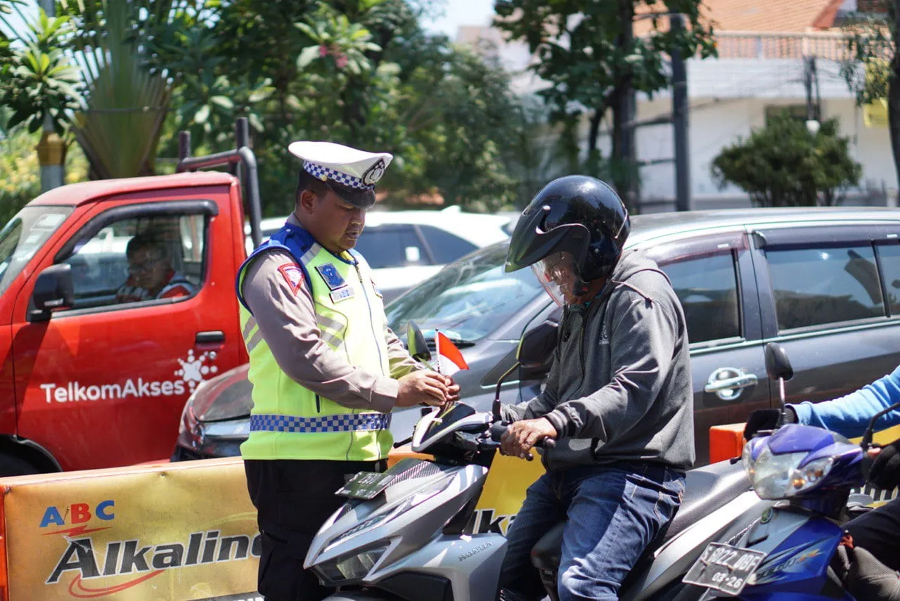 Satlantas Polrestabes Surabaya Bagikan Bendera Merah Putih ke Pengguna Jalan